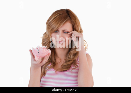 Bionda donna che piange mentre si tiene il suo rotto piggybank Foto Stock