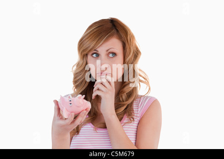 Bionda donna perplesso riguardante il suo rotto piggybank Foto Stock