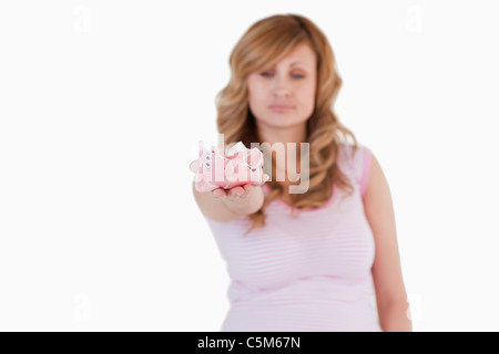 Carino bionda donna che mostra il suo rotto piggybank Foto Stock