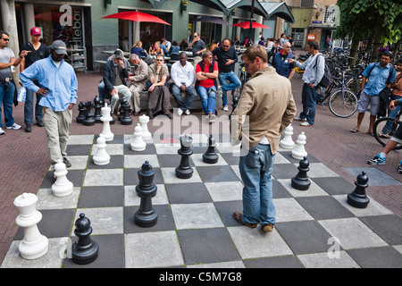 Gli uomini che giocano a scacchi con pavimentazione piazze e pezzi, in Max Euwe-Plein, Amsterdam, Paesi Bassi Foto Stock