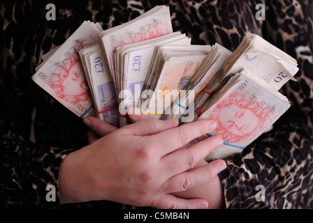 Un close-up di una donna di mani che impugnano un piccolo-fortune di mazzette di banconote. Foto Stock