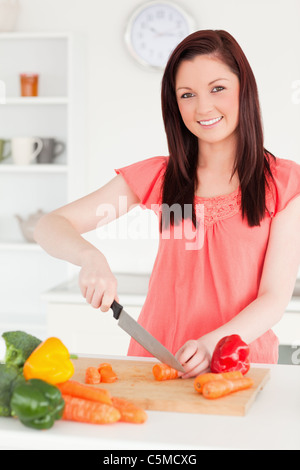 Bellissimi i capelli rossi donna il taglio di alcune carote in cucina Foto Stock