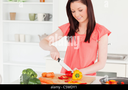 Stupendo i capelli rossi donna il taglio di alcune carote in cucina Foto Stock