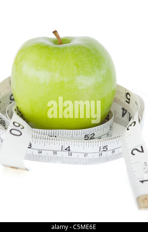 Primo piano di una mela verde cerchiato con un nastro di misurazione Foto Stock