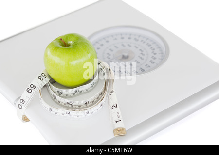 Mela Verde cerchiato con un metro a nastro e pesare-scala Foto Stock