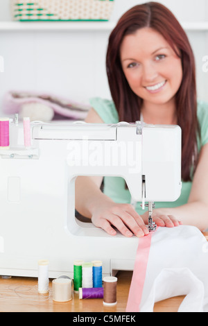 Affascinanti i capelli rossi donna utilizzando una macchina di cucitura Foto Stock