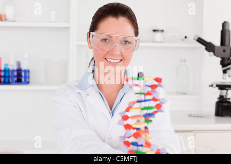 Sorridente scienziato che mostra la doppia elica del DNA modello Foto Stock