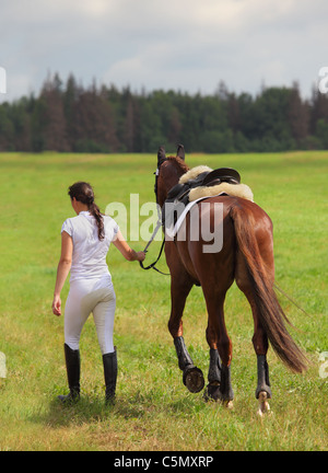 Una giovane ragazza appoggiata al suo cavallo a un evento equestre Foto Stock