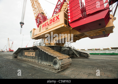 Un enorme gru essendo utilizzato per caricare pices per la Walney offshore wind farm presso il molo di Barrow in Furness, Cumbria, Regno Unito. Foto Stock