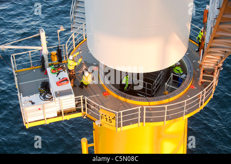 Un pezzo di torre di essere abbassato su una turbina a vento sulla base dell'Walney offshore wind farm, Cumbria, Regno Unito. Foto Stock