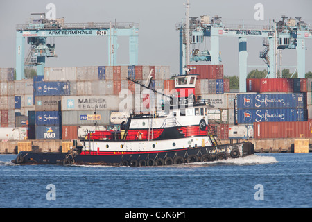 Un rimorchiatore di Norfolk rimorchiatore passa la P.A. Moller-Maersk facility nel porto Newark-Elizabeth Terminale Marino nella baia di Newark. Foto Stock