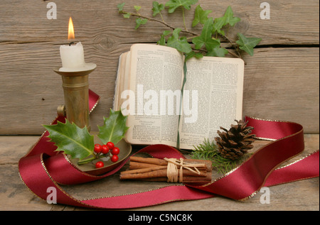 Tema Natale ancora in vita con una candela e libro di preghiera Foto Stock