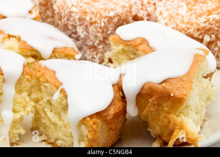 Madeleines tradizionale rivestito in marmellata e coperto con un pizzico di noce di cocco. Foto Stock