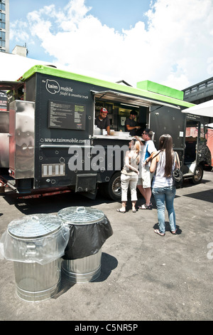 Clienti felici linea fino a falafel carrello alimentare nel lotto accanto alla linea alta elevato ingresso parco di quartiere di Chelsea di New York City Foto Stock