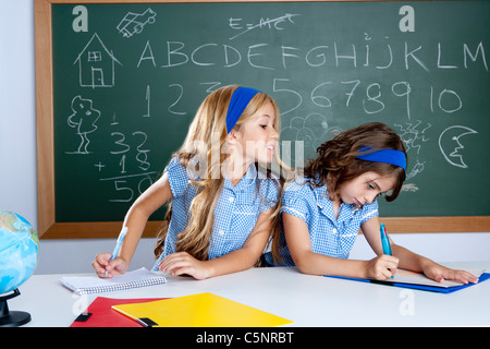 Aula con due bambini studenti barare in esame di prova a scuola Foto Stock