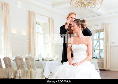 La stilista pinning di una sposa acconciatura prima del matrimonio Foto Stock
