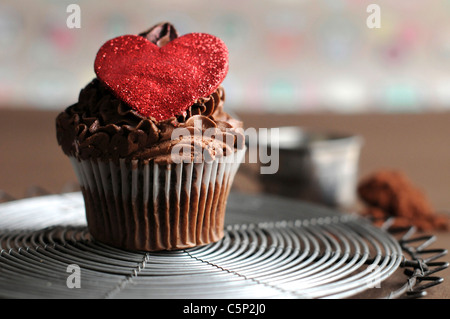 Tortina di cioccolato con zucchero rosso cuore sulla parte superiore Foto Stock