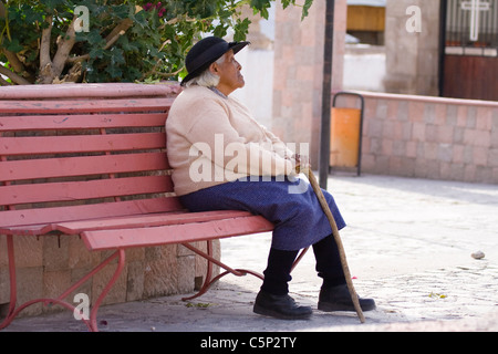 Aymara vecchia donna seduta su una panchina alla Plaza de Armas, Putre, Cile, Sud America Foto Stock