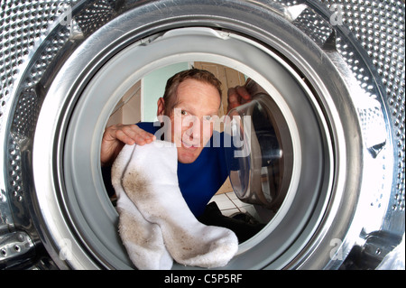 Uomo di mettere dei calzini sporchi nella macchina di lavaggio Foto Stock