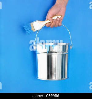 Una persona in possesso di un secchio di vernice Foto Stock