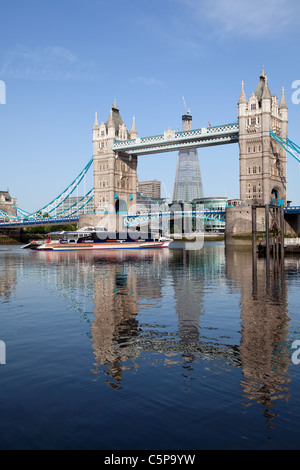 Frammento di Londra e al Tower Bridge si riflette nel fiume Tamigi come Thames clipper commuter traghetto passa. Foto Stock