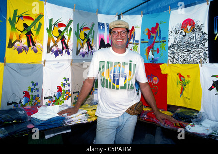 Un venditore ambulante in Rio de Janeiro vende i turisti e locali colorati brasiliani T-shirt con uccelli tropicali e altri simboli del Brasile e Sud America. Foto Stock