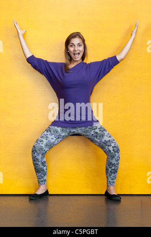 Bella ragazza in viola maglione su uno sfondo di colore giallo parete in legno Foto Stock