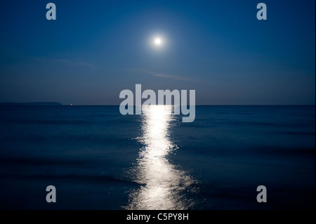 Moonlight invia una riflessione su una notte tranquilla mare dalla costa di Highcliffe, Dorset. Foto Stock