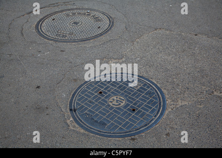 Scarico fognario copre nelle strade di Pechino, Cina Hutong Village Foto Stock