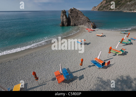Sedie a sdraio e ombrelloni sono allineate in modo ordinato sulla spiaggia, al mattino presto prima di andare in spiaggia, con lunghe ombre portate. Foto Stock