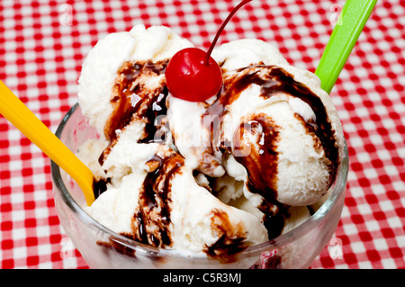 Gelato alla vaniglia e cucchiai con la ciliegia e cioccolato Topping Closeup Foto Stock