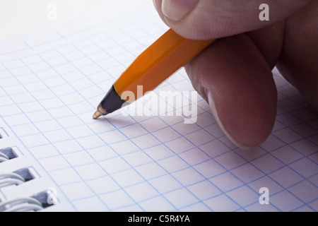 Mano d'uomo facendo una penna scrittura in un notebook Foto Stock