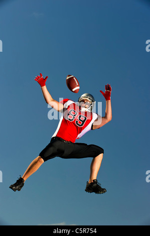 Giocatore di football americano dei salti per effettuare la cattura. Foto Stock