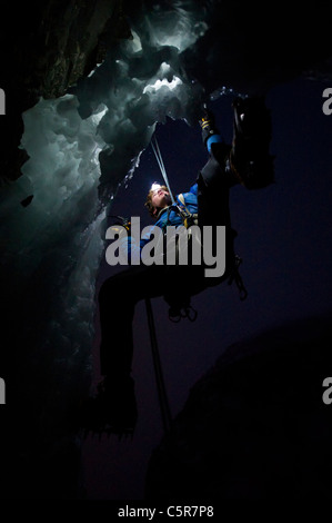 Arrampicata su ghiaccio di notte sul bordo di una grotta. Foto Stock