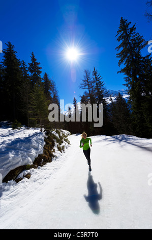 Una ragazza jogging in alta quota in montagna innevata. Foto Stock