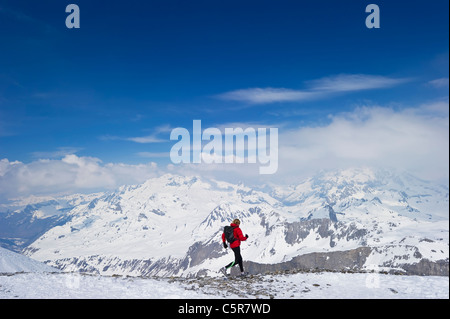 Esecuzione del pareggiatore tramite snowy mountain range. Foto Stock