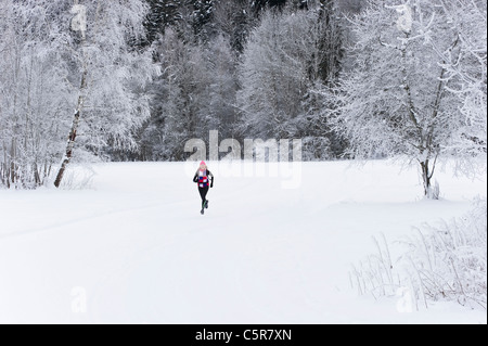 Un pareggiatore in esecuzione attraverso un paesaggio innevato. Foto Stock