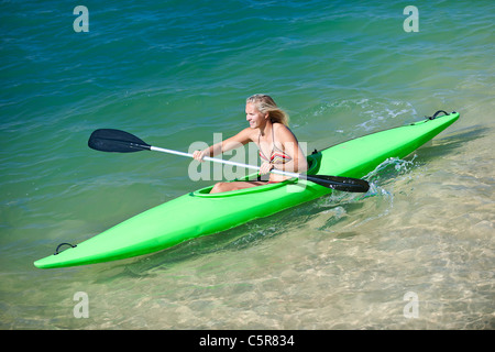 Una donna pagaie la sua canoa in una giornata di sole. Foto Stock