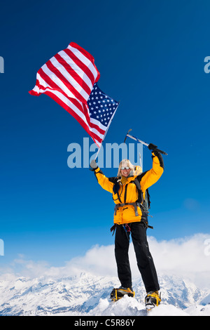 Alpinista celebrando in cima al mondo battenti a stelle e strisce Foto Stock