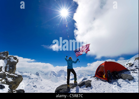 Scalatore celebra sulla cima della montagna innevata. Foto Stock