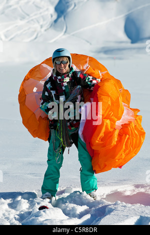 Un pilota di parapendio sorrisi con ala sopra la sua spalla. Foto Stock