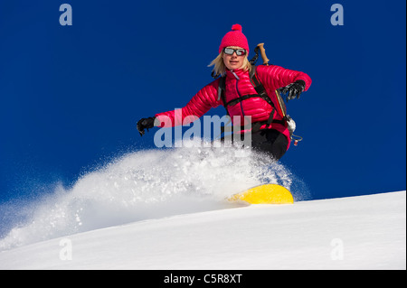 Uno snowboarder rides profondo di polvere fresca neve a velocità. Foto Stock