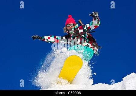 Una femmina di snowboarder equitazione duro attraverso una profonda di polvere fresca neve. Foto Stock