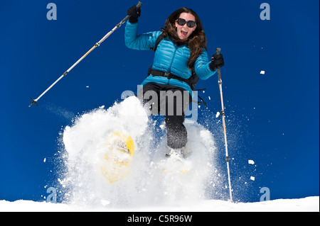 Una donna con le racchette da neve e divertimento in fresco in polvere di neve. Foto Stock