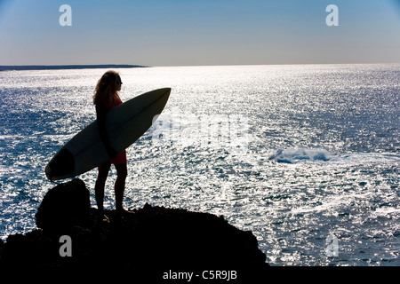 Un surfista si affaccia sull'oceano scintillante Foto Stock