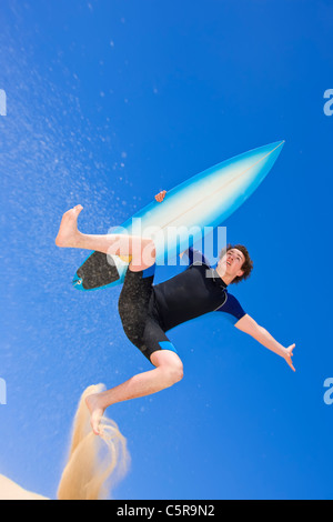 Surfer salti di spiaggia di dune di sabbia. Foto Stock