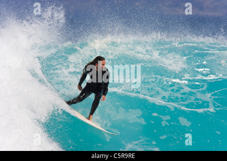 Un surfista cavalca un incredibile blu azzurro oceano onda. Foto Stock
