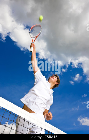 Un giocatore di tennis si estende in alto sopra la rete di smash ball per set point. Foto Stock