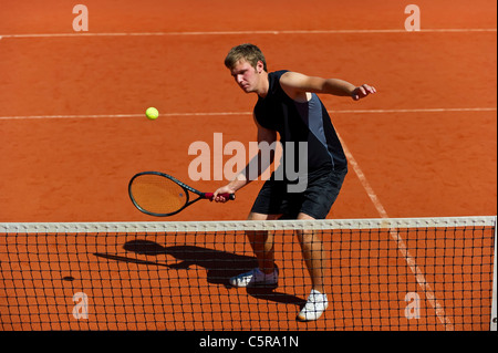 Un giocatore di tennis fino in prossimità della net si concentra su volley Foto Stock