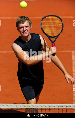 Un giocatore di tennis sorrisi come egli si prepara a beach volley. Foto Stock